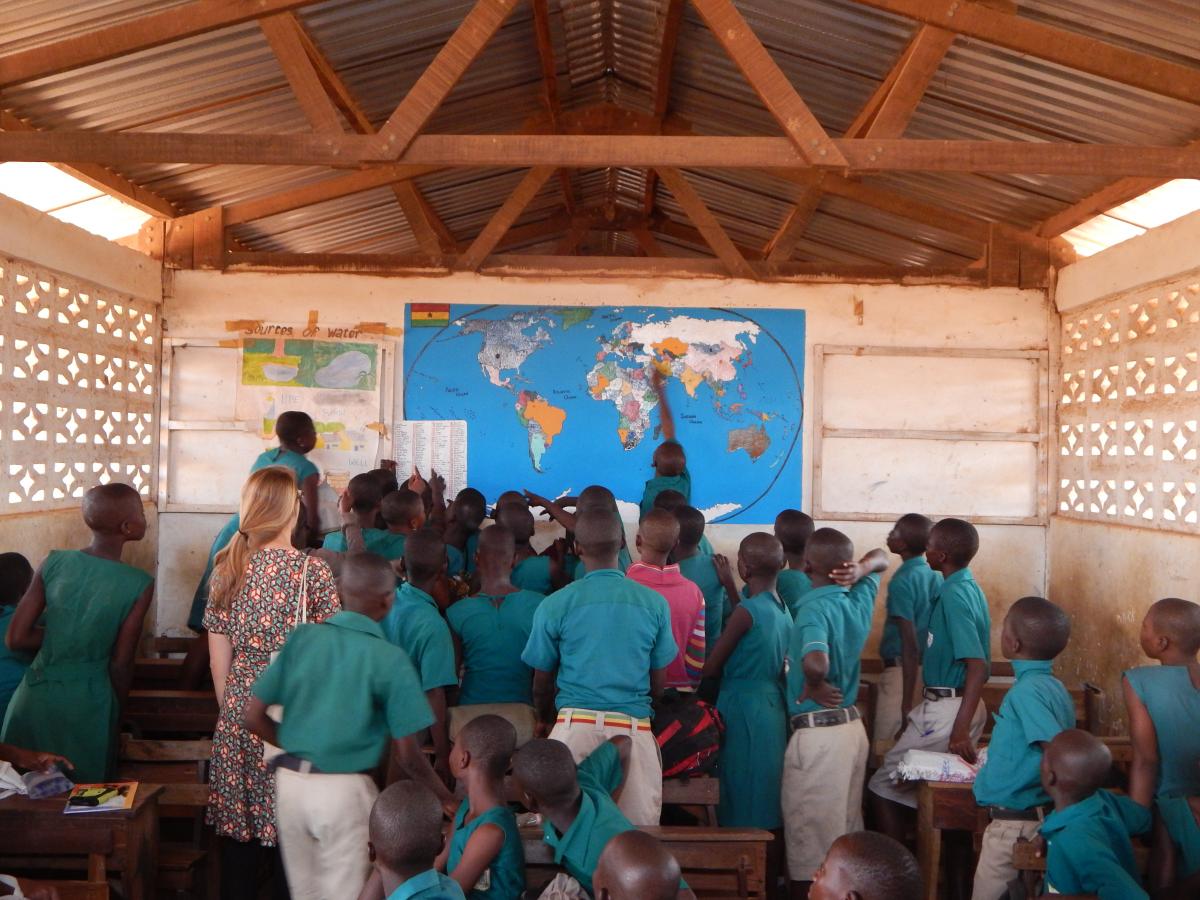 Ghanaian students point to a map on a classroom wall